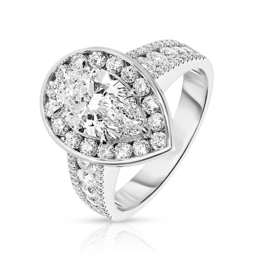 Experience the mystical elegance of the night sky with the "Tear of the Moon" Gold ring. This exquisite halo ring showcases a captivating pear-cut diamond at its heart, symbolizing the rare beauty of a moonlit tear. Encircled by a halo of shimmering diamonds, each stone glistens like stars against the Gold setting, evoking a celestial radiance that enchants and mesmerizes.